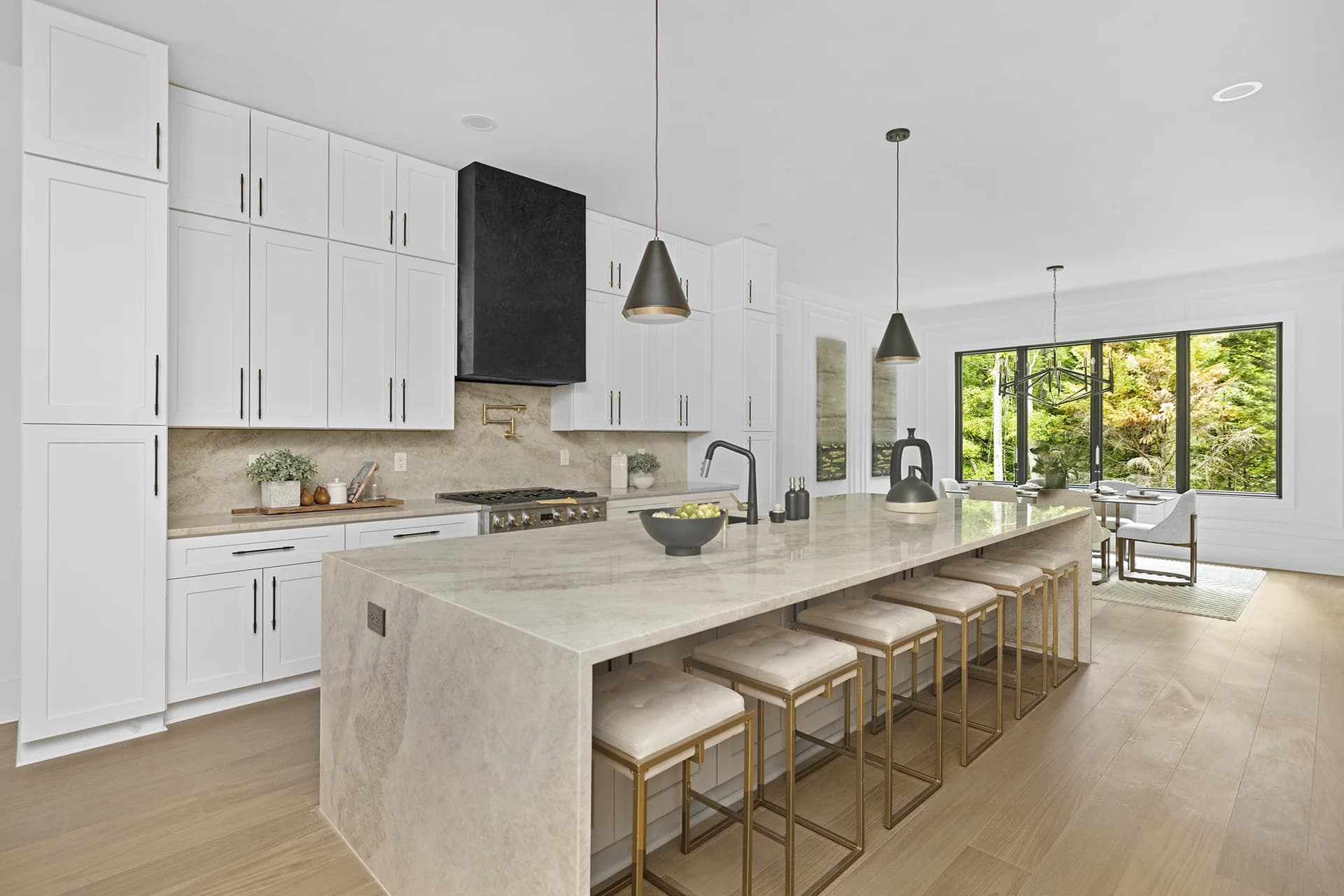 Bright custom kitchen with a stone island, brass lighting and wood cabinetry