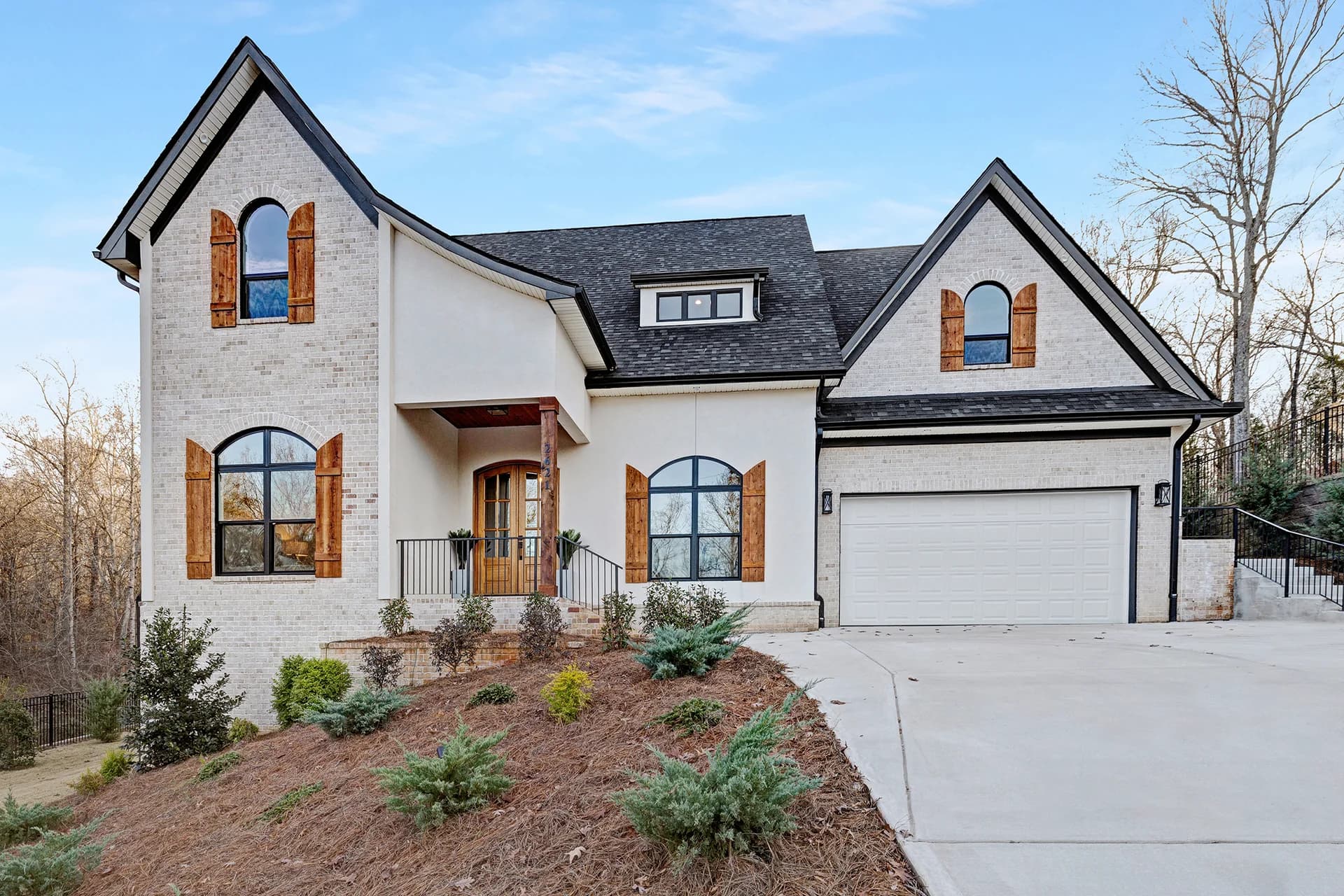 White brick home with steep gables, an arched front door and a landscaped entrance on Ski Trail Lane