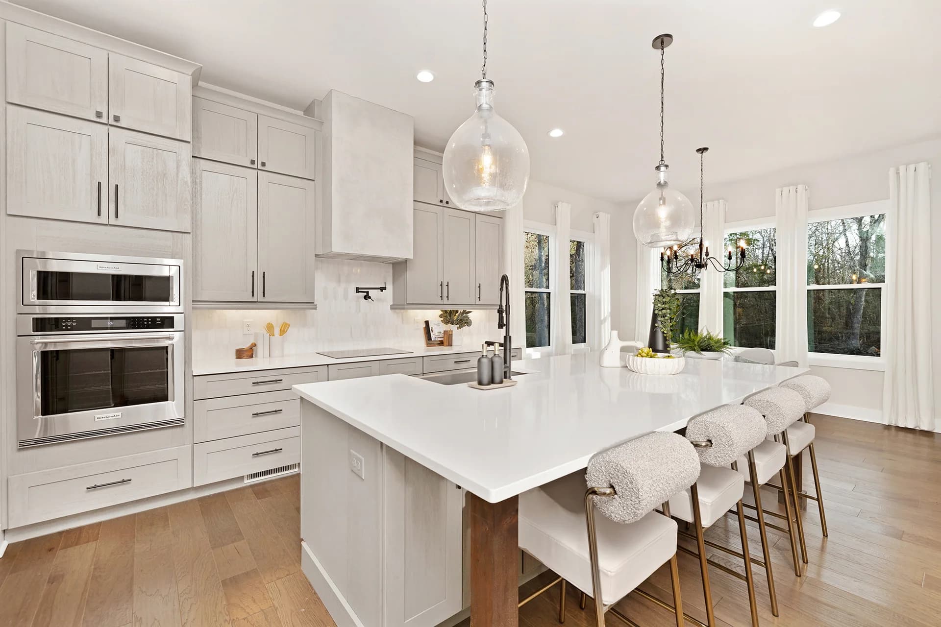 White kitchen with an island, upholstered stools and pendant lighting at Ski Trail Lane